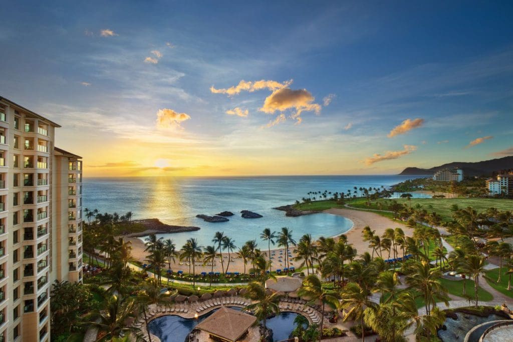 An aerial view of Marriott's Ko Olina Beach Club, one of the best resorts for families in O'ahu, featuring pristine resort grounds, beach access, pools, and a stunning sunset.