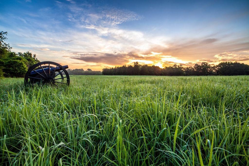 The Stones River National Battlefield, featuring a cannon in the grass at dusk.