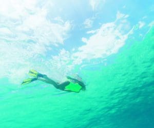 A young girl dives in the ocean water, greenish-blue in color.