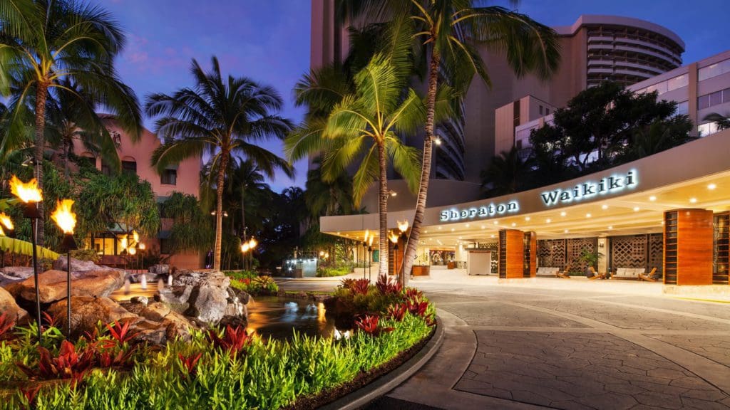 The drive up to Sheraton Waikiki, featuring lush foliage and a well-lit entrance at night, one of the best resorts for families in O'ahu.