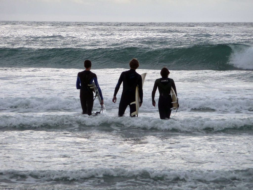 Three surfers preparing to surf at Cardiff-by-the-Sea surf spot, Cardiff Reef.