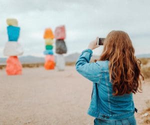 A woman takes a picture of Seven Magic Mountains near Las Vegas.
