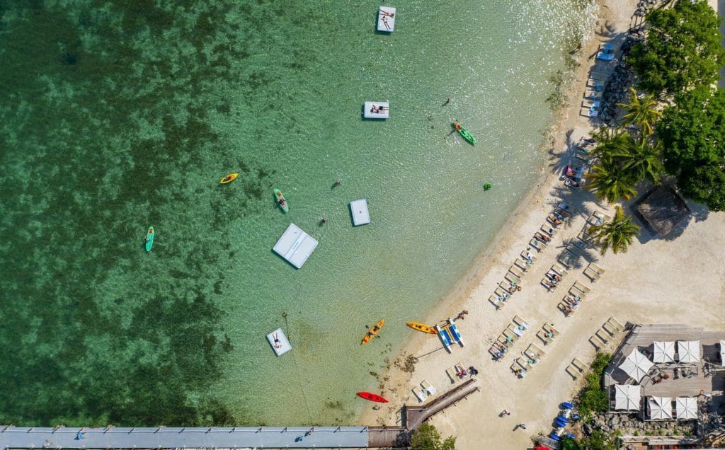 An aerial view of boats off-shore from the beach along the grounds of Baker's Cay Resort Key Largo, Curio Collection By Hilton, one of the best Hilton Hotels in the United States for families.