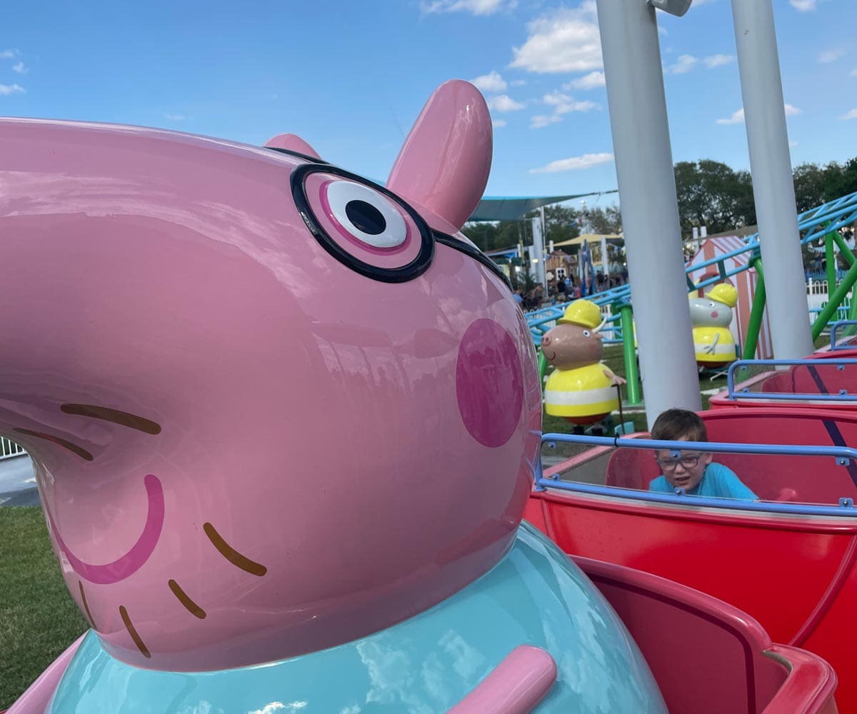 A close up of two kids riding in a Daddy Pig ride at Florida's Peppa Pig Theme Park.