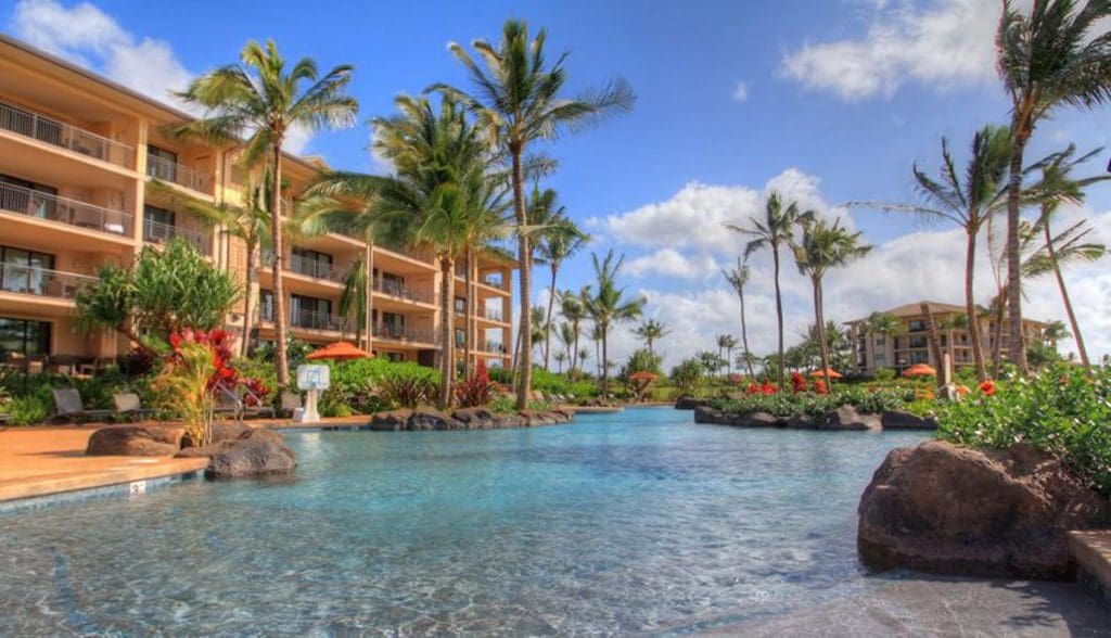 The large pool, with resort buildings and palm trees in the background, at Koloa Landing Resort at Poipu, Autograph Collection.