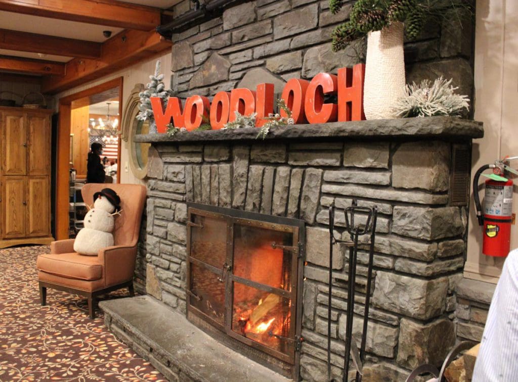 The iconic Woodloch Resort fireplace, featuring its name in red print blocks along the mantle. 