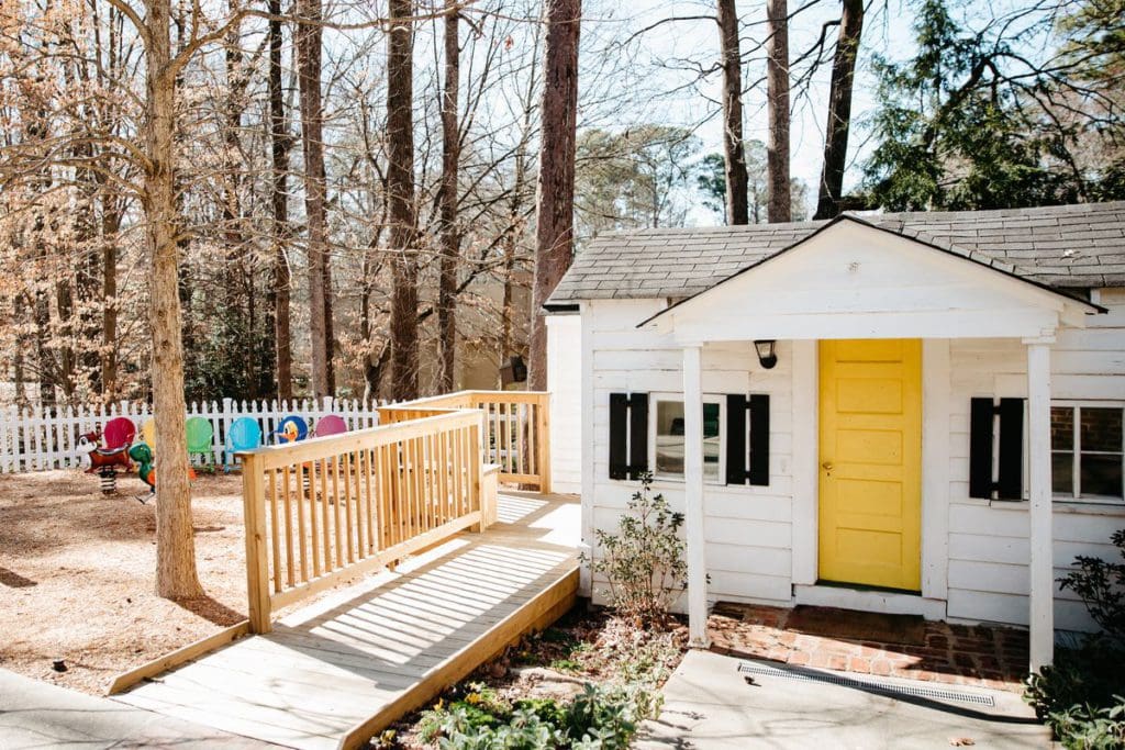 The outdoor playhouse at the Atlanta History Center, featuring a wooded area for kids to play and colorful chairs for parents to watch on.