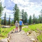 Two small kids walk together along a hiking path in Colorado.