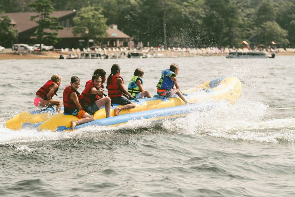 Six kids ride on a large tube, pulled by a boat on the lake, while staying at Grand View Lodge Spa & Golf Resort.