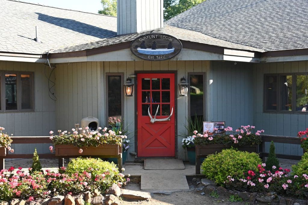 The entrance to Gunflint Lodge & Outfitters, with a large red door and beautiful summer flowers out front.