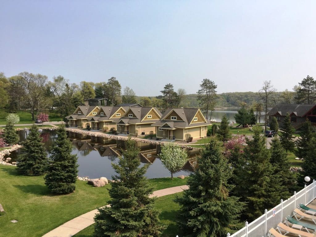 An aerial view of Kavanaugh’s Sylvan Lake Resort, featuring a large resort building, charming pine trees, and its lakeside locaiton.