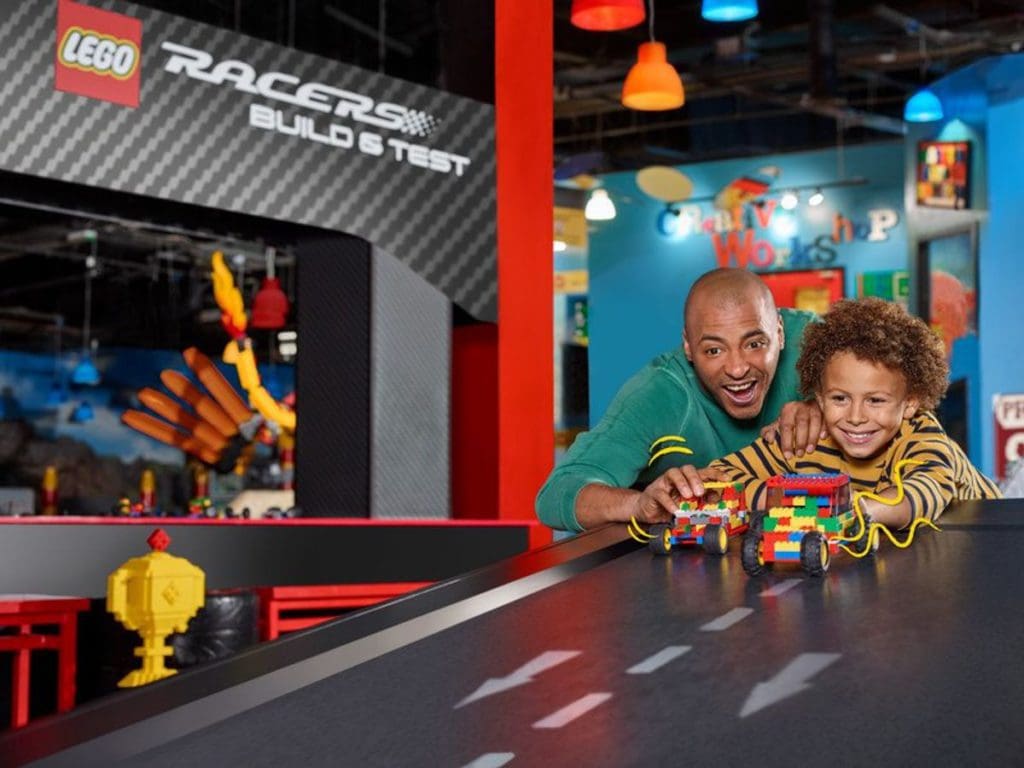 A dad and his son race lego cards down a track at Legoland Discovery Center (Somerville, MA).