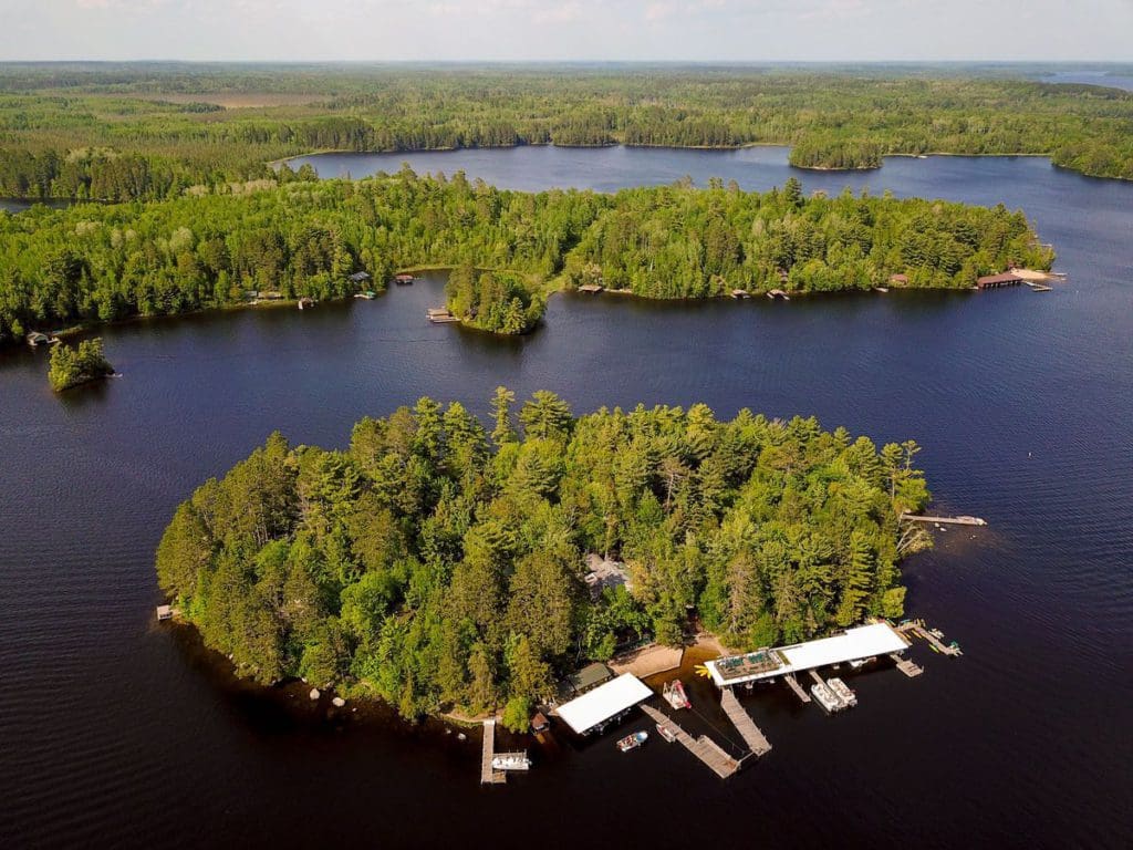An aerial view of Ludlow’s Island Resort, a heavily wooded island on a beautiful lake, one of the best summer resorts in Minnesota for families