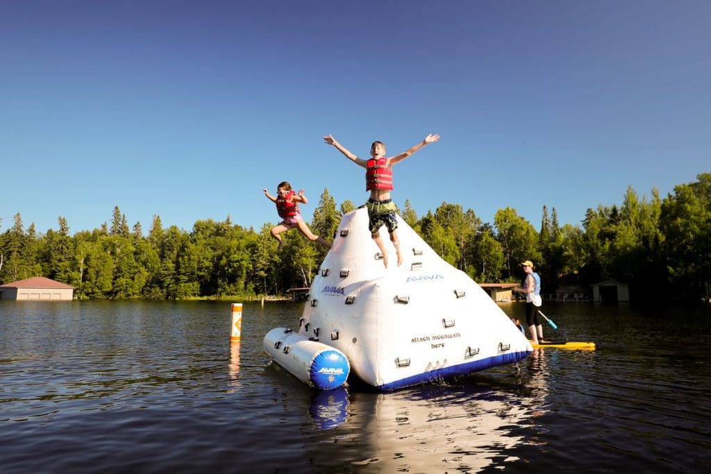 Two kids jump from a large blow-up floatation device, while staying at Ludlow’s Island Resort.
