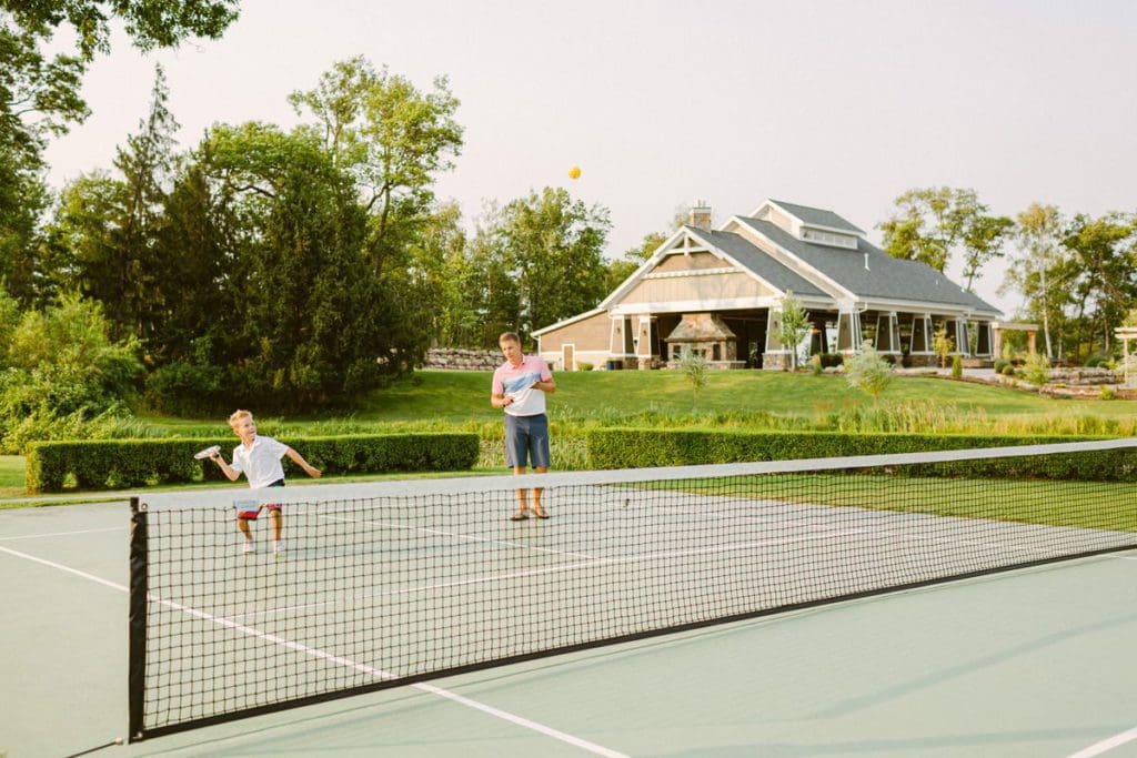Two kids playing tennis on a summer evening at Madden’s On Gull Lake.