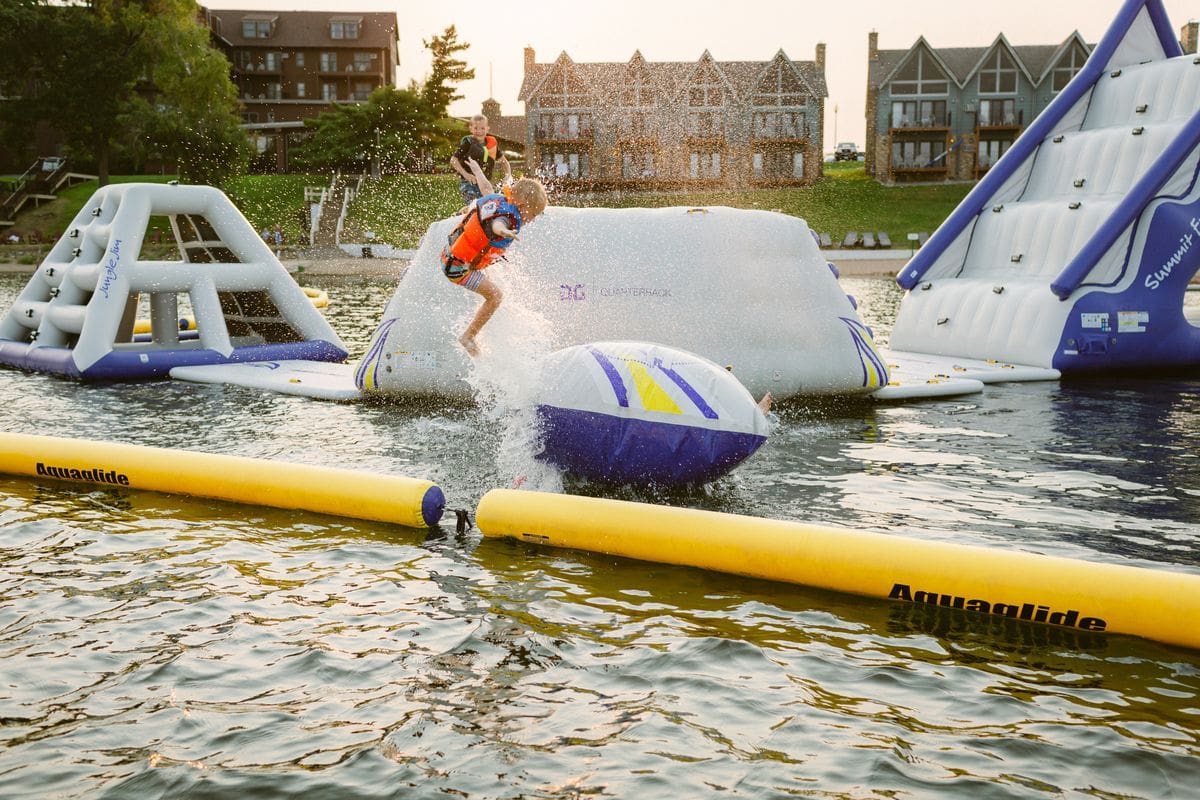 A child jumps from a huge flotation device on the lake, off-shore from Madden’s On Gull Lake, one of the best all-inclusive hotels in the United States for families.