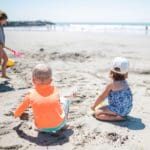Three kids play on a beach near San Diego, with their own sand toys.