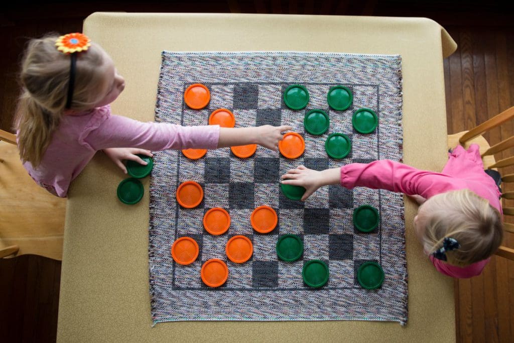 An overhead view of two kids playing checkers, while staying at Skyport Lodge & Raven Rock Grill.