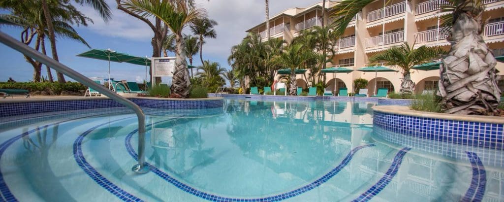 The large pool at Turtle Beach by Elegant Hotels, with resort buildings in the background, one of the best resorts in Barbados for a family vacation.