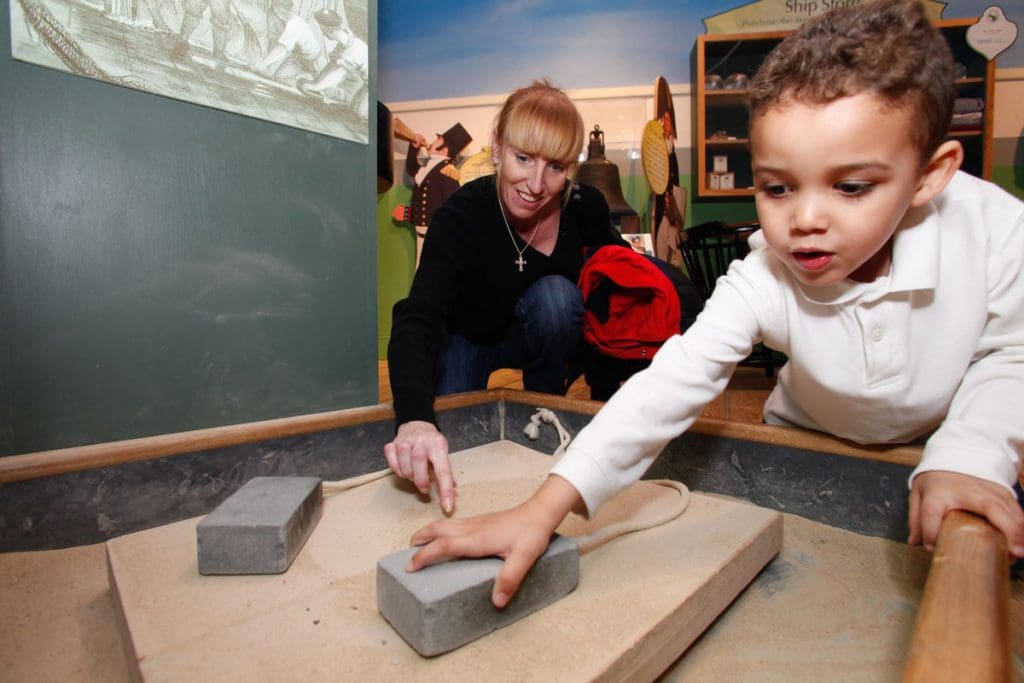 A young boy and his mom interact with an exhibit at the USS Constitution Museum, one of the best things to do in Boston with kids.