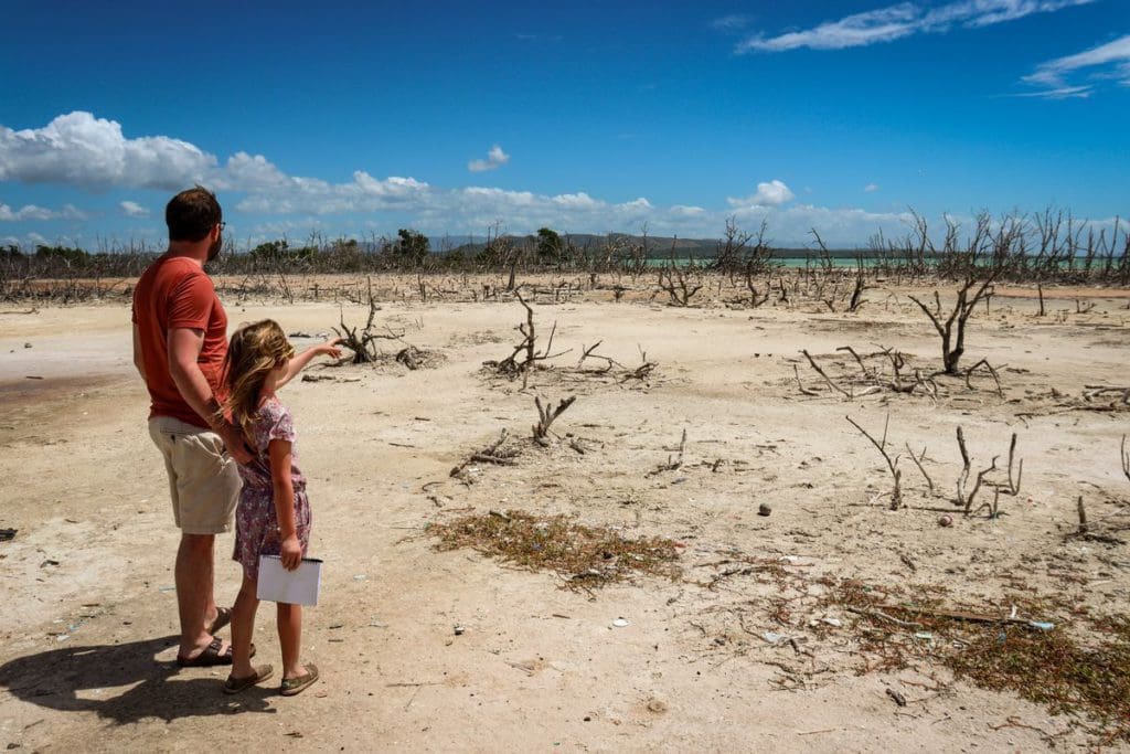 A dad and his young daughter stand together while the young girl points out onto a desert scene in Cabo Rojo National Wildlife Refuge in Puerto Rico. Knowing the best things to do in Puerto Rico for families is part of knowing All About Puerto Rico With Kids!