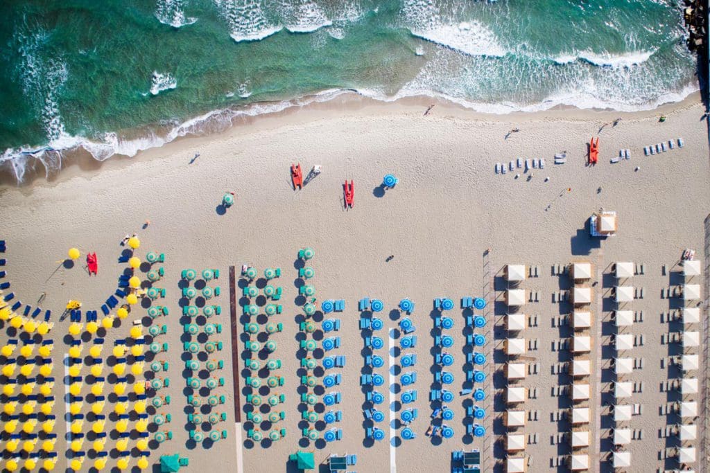 An aerial view of lines of brightly colored umbrellas on the beach of Forte Dei Marmi, one of the best beach destinations in Europe for families.