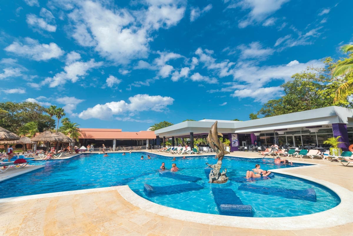 Several people enjoy the pool on a sunny day at Hotel Riu Lupita, one of the best all-inclusive resorts Playa del Carmen for families.