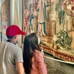 Two kids stand together and admire a painting, while exploring a museum.