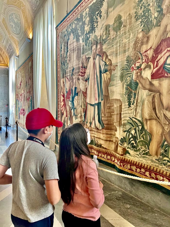 Two kids look at a piece of art inside the Vatican Museum.