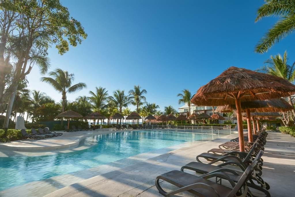 The large pool and surrounding pool deck, with poolside loungers, at Sandos Caracol Eco Resort, one of the best all-inclusive resorts Playa del Carmen for families.