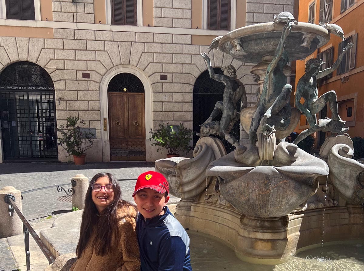 Two kids sit on the edge of Turtle Fountain in Rome.