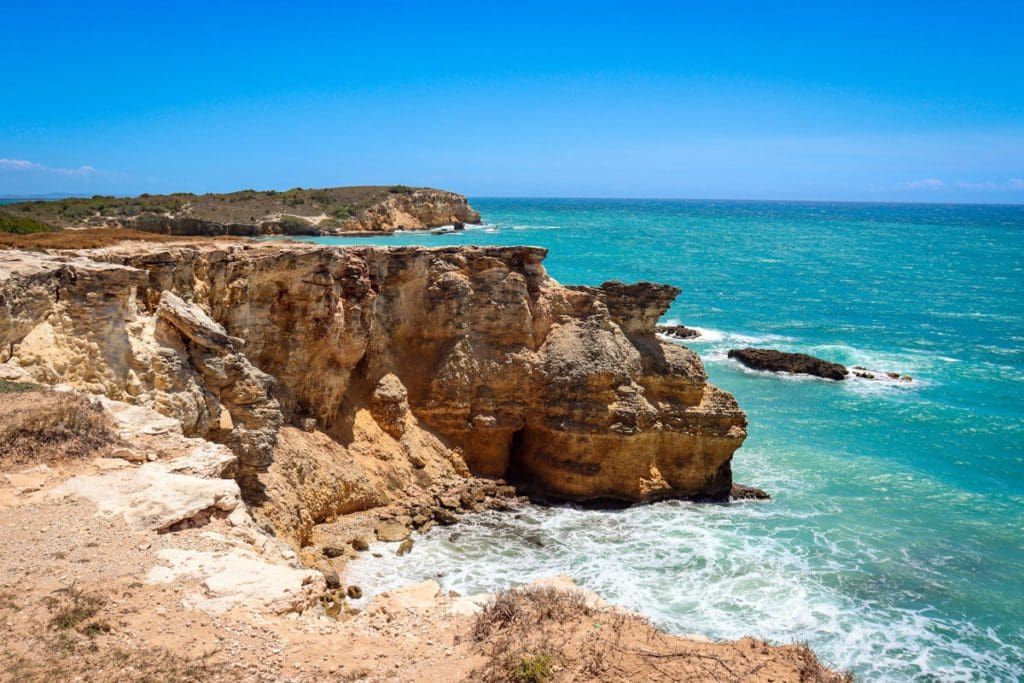 Large stone cliffs stand proudly over the ocean waters in Cabo Rojo National Wildlife Refuge, a must stop on any Puerto Rico itinerary for families.
