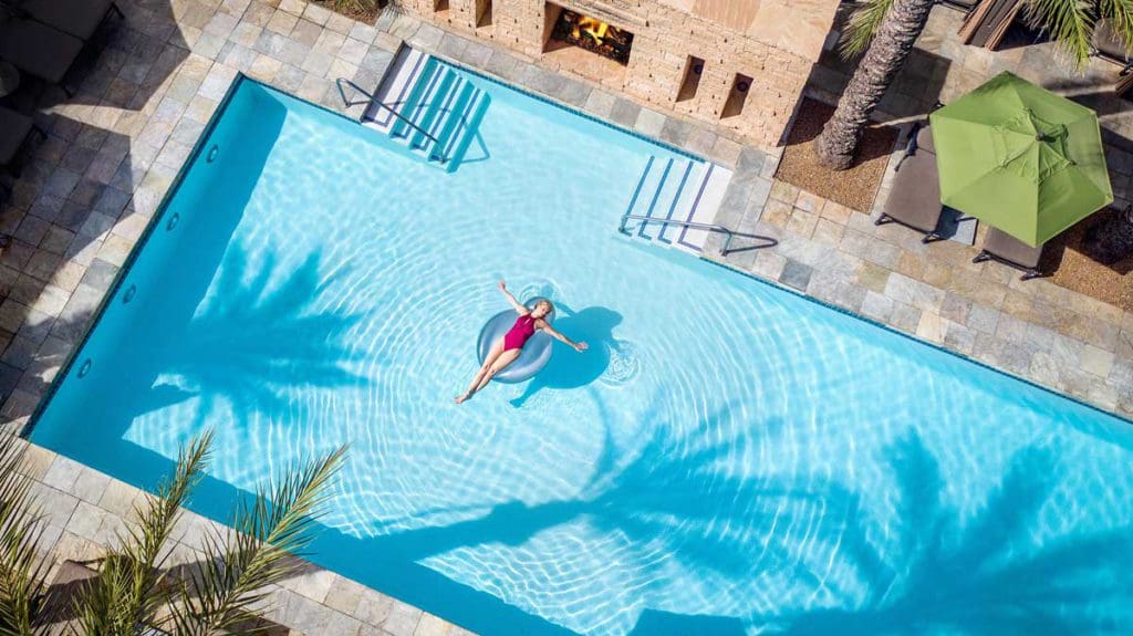 A woman lounging on a pool floatie in a crystal blue pool at the Fairmont Scottsdale Princess, one of the best luxury hotels in the U.S for families. 