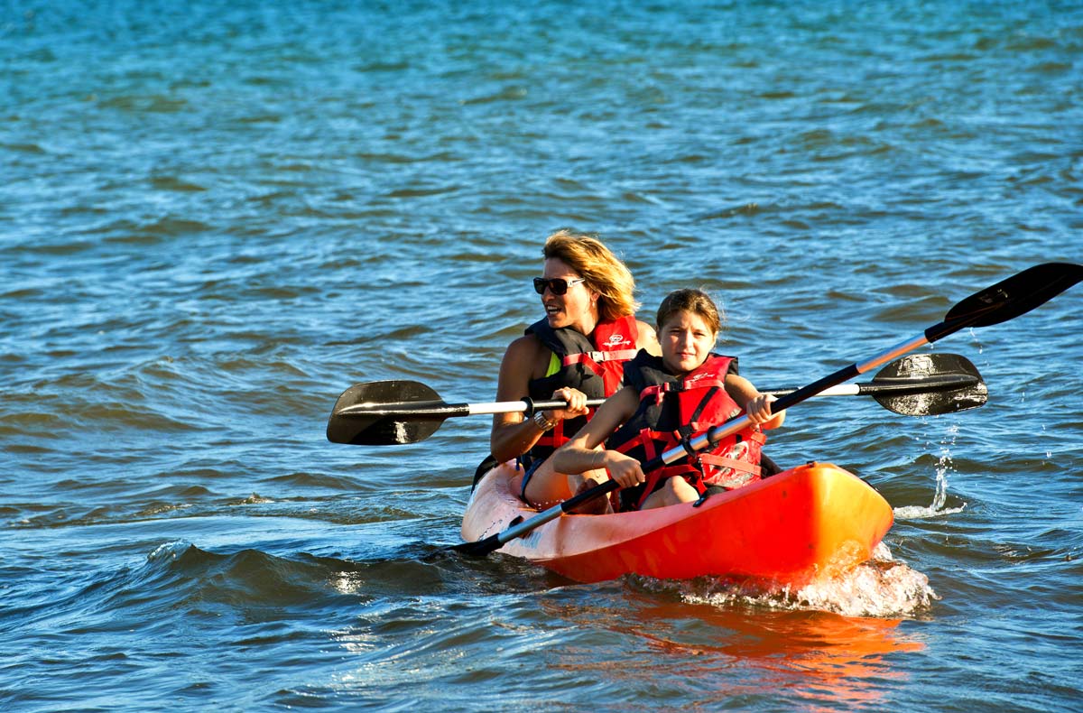 A mom and her son kayak off-shore from Hopkins Bay Belize, a Muy’Ono Resort, one of the best Belize resorts for a family vacation.