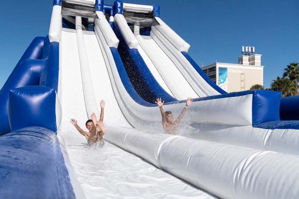Two kids shoot down a large inflatable water slide at Tradewinds Island Grand Resort.