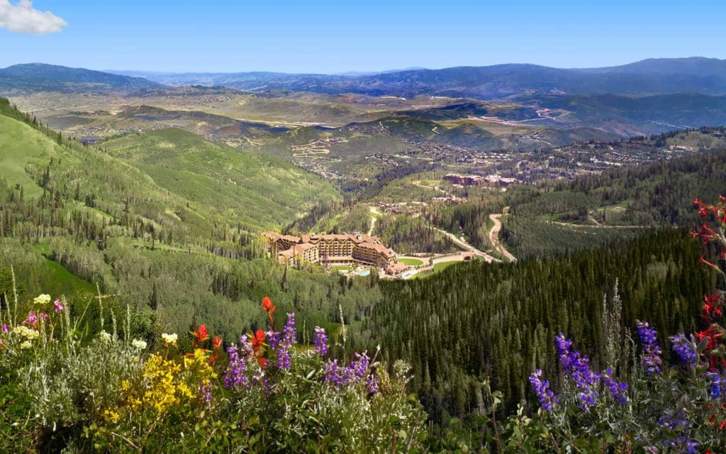 A beautiful aerial view of Montage Deer Valley during the spring time, when the hotel is surrounded by verdant plants and blooming wildflowers.