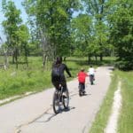 A mother and two sons riding a bike through a grassy path in Northern Illinois.