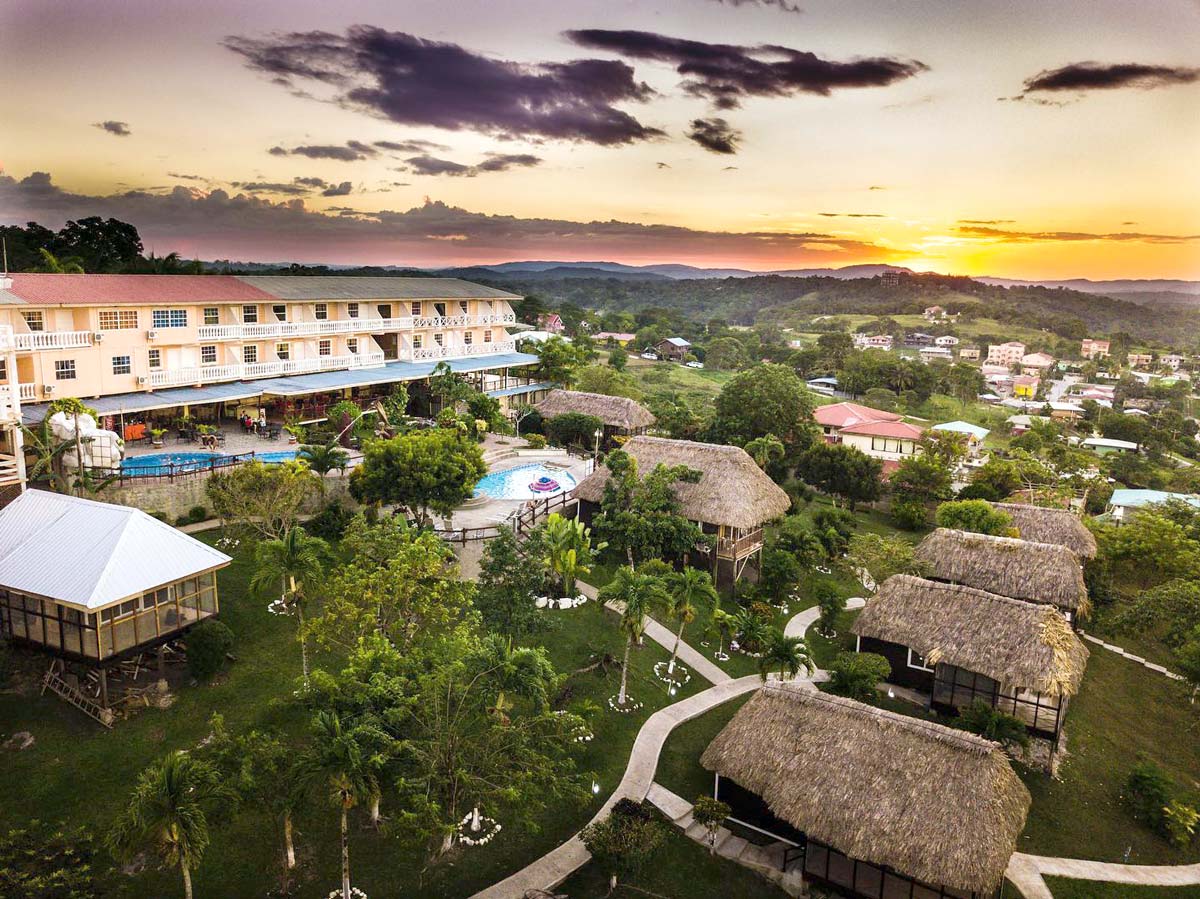 An aerial view of Cahal Pech Village Resort, featuring its lush grounds at sunset at one of the best Belize resorts for a family vacation.