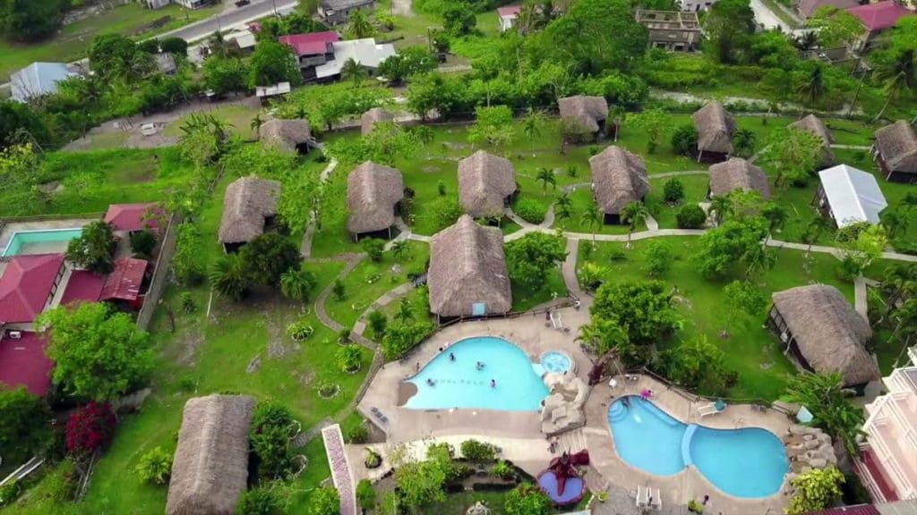 An aerial view of the pool and surrounding villas with thatch roofs at Cahal Pech Village Resort.