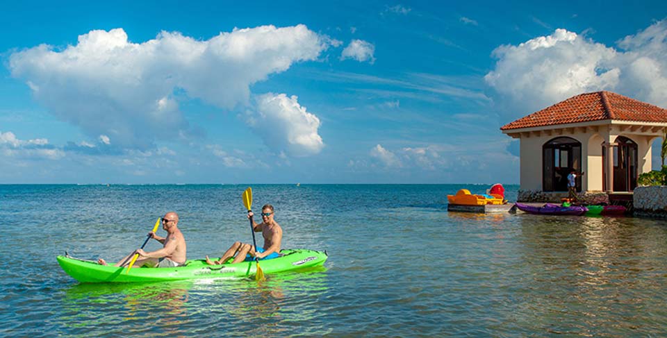 A couple kayaks along the water near Coco Beach Resort, one of the best Belize resorts for a family vacation.