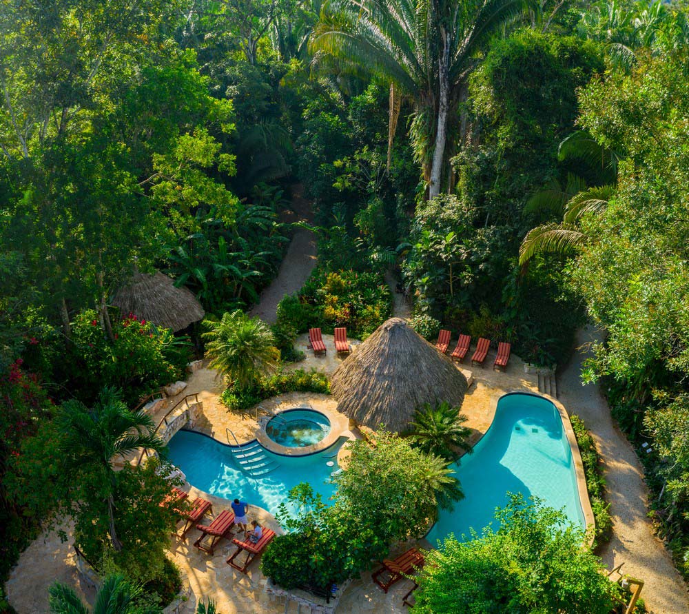 An aerial view of the intimate pool area and surrounding pool deck, surrounded by tropical rainforest, at Ian Anderson's Caves Branch Jungle Lodge.
