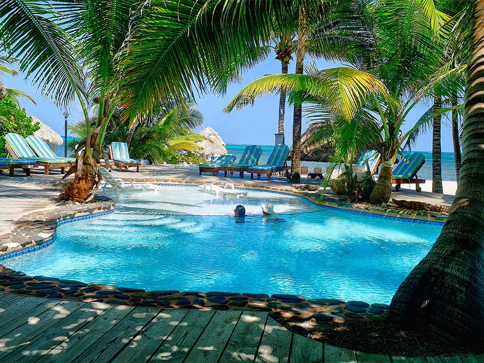 Two people swim in the beautiful outdoor pool at Xanadu Island Resort, one of the best Belize resorts for a family vacation.