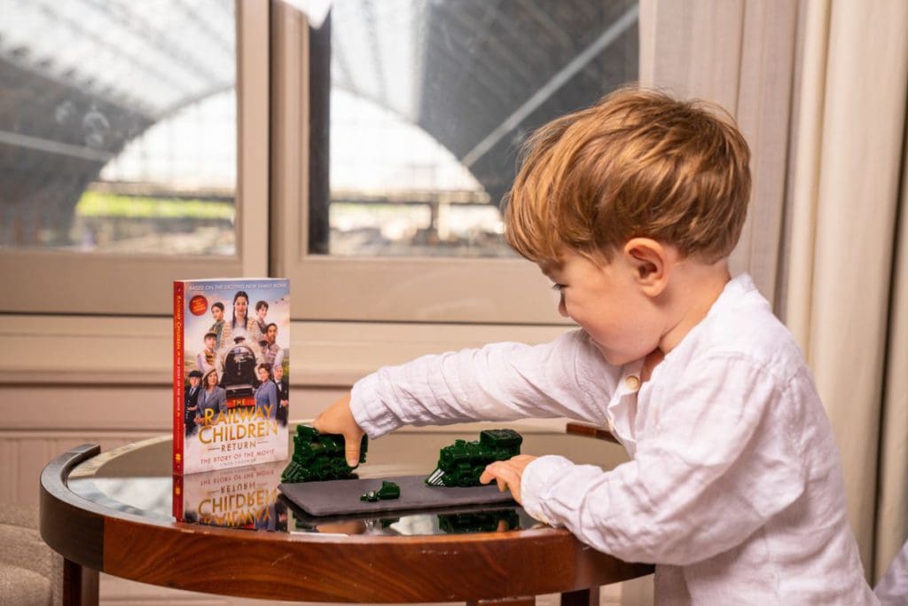 A young boy plays with a train set near a beloved British Novel at St. Pancras Renaissance Hotel.