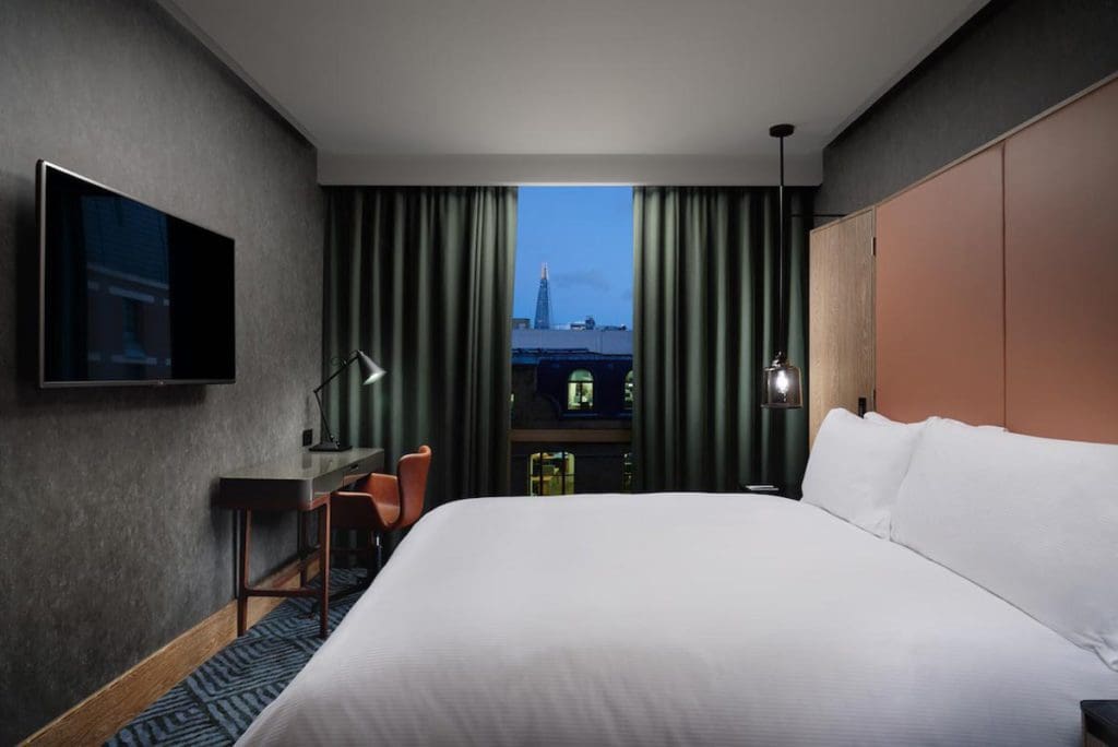 Inside a Deluxe Suite at the Hilton London Bankside, featuring a large bed and city view.