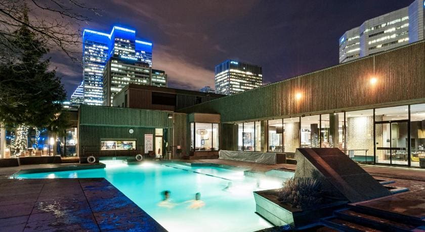 Two people swim in the rooftop pool of the Hotel Bonaventure Montreal at night.