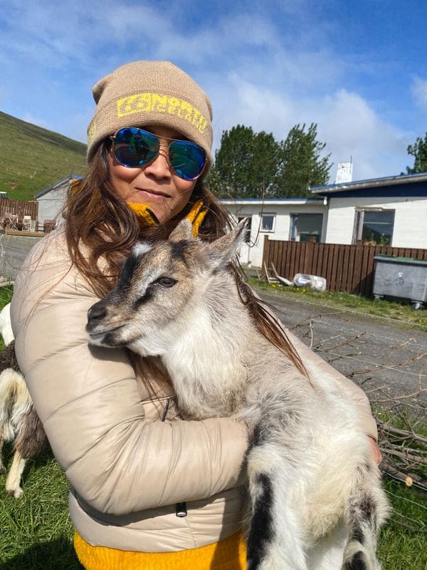 A woman snuggles with a baby goat.