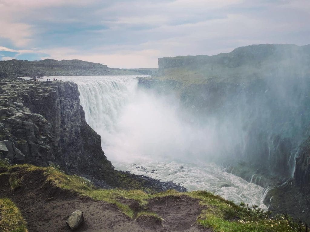 The Dettifoss Waterfall, misting into the river, and surrounded by cliffs.