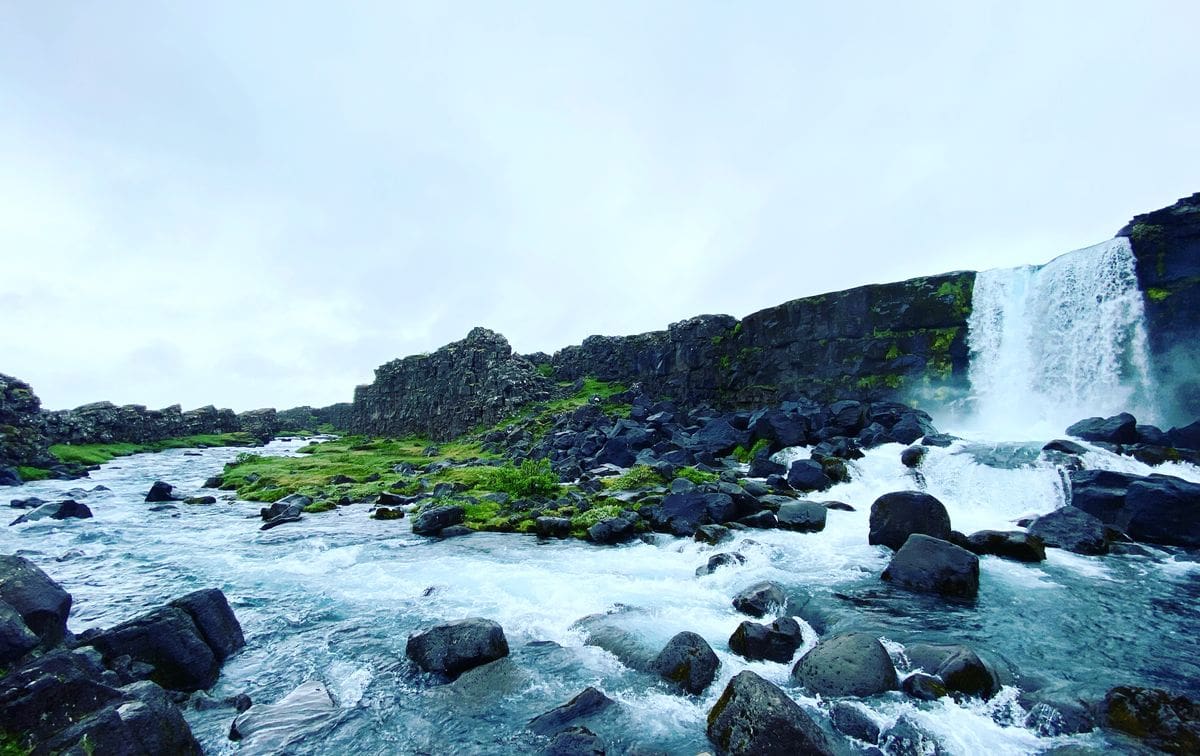 A waterfall amongst large rocks within Thingvellir National Park, a must stop on any Iceland itinerary for families.