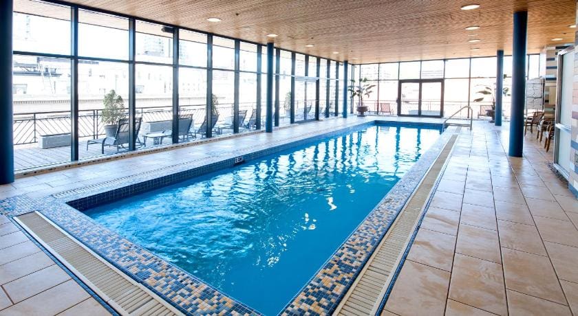 The charming indoor pool, with large windows surrounding it, at Le Square Phillips Hôtel & Suites.
