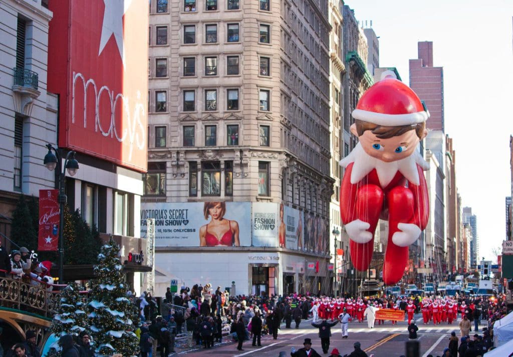 A large Elf on the Shelf float makes its way down a NYC street during the Macy's Thanksgiving Day Parade.